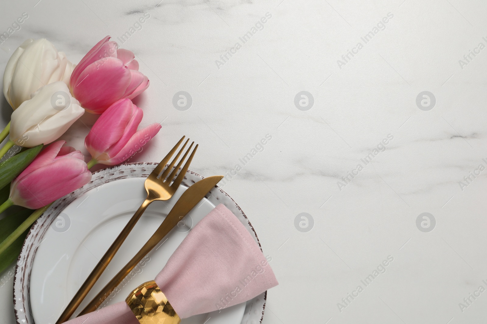 Photo of Stylish table setting with cutlery and tulips on white marble background, flat lay. Space for text