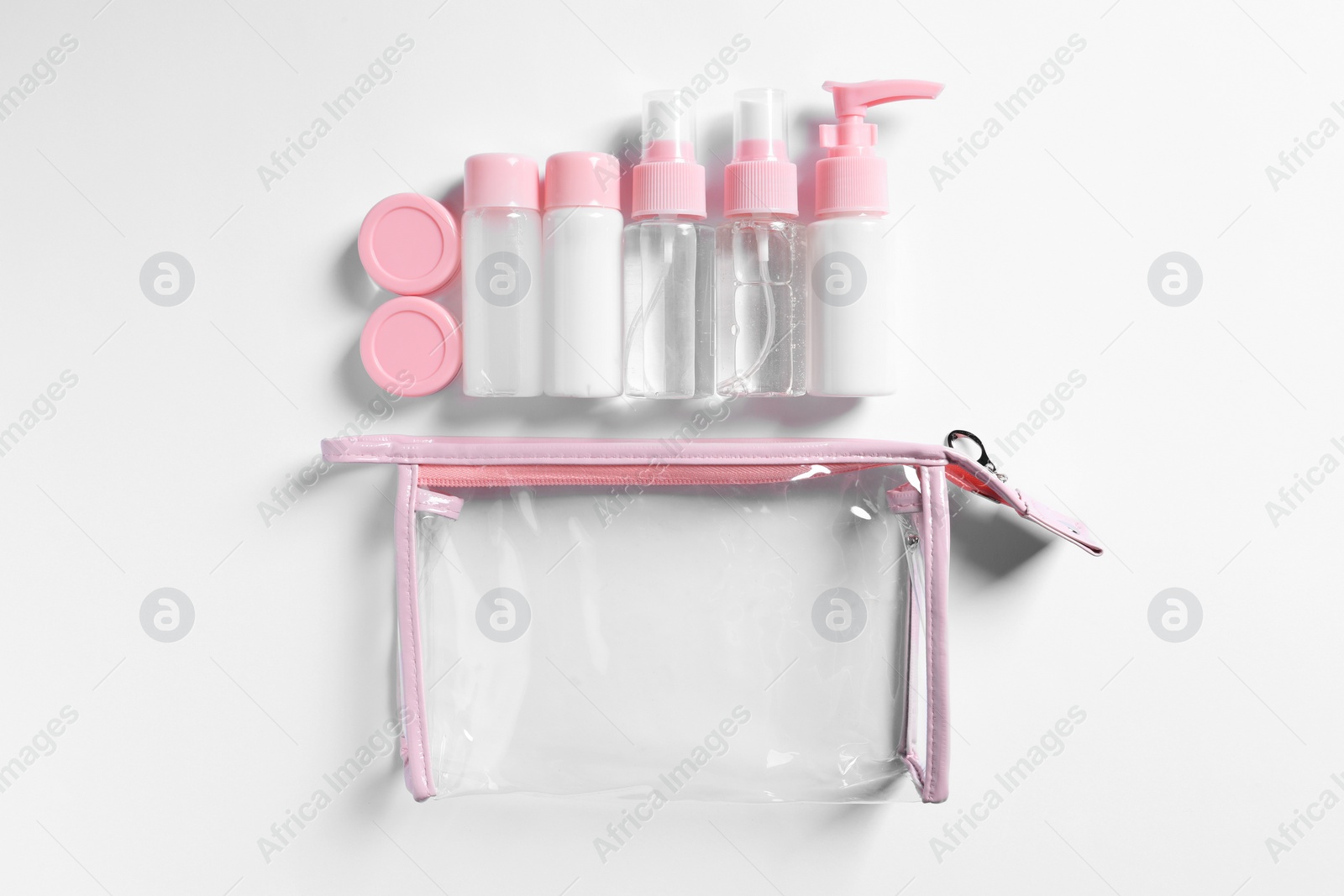 Photo of Cosmetic travel kit and plastic bag on white background, flat lay