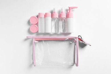 Cosmetic travel kit and plastic bag on white background, flat lay