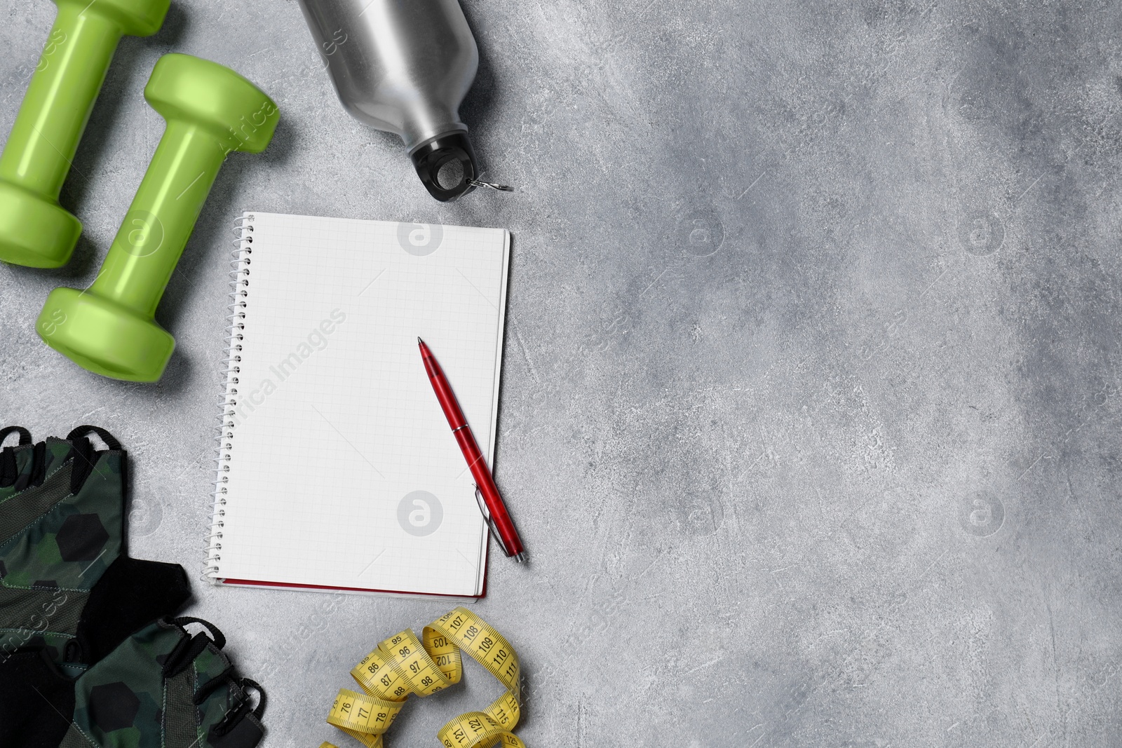 Photo of Notebook, pen and sports equipment on grey table, flat lay with space for text. Personal training