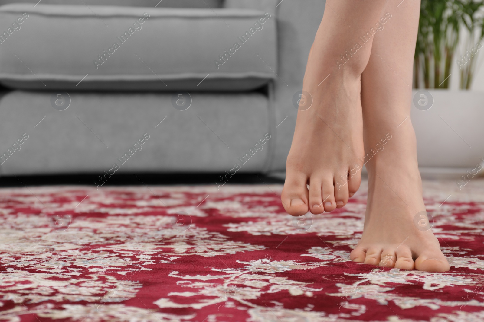 Photo of Woman standing on carpet with pattern at home, closeup. Space for text