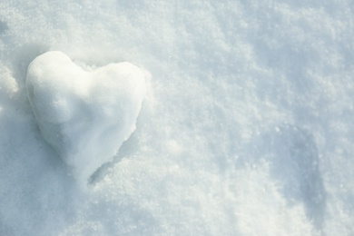 Photo of Heart shaped snowball on snow, top view. Space for text