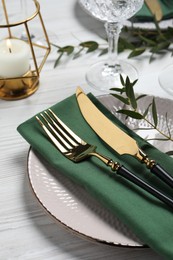 Photo of Stylish setting with cutlery and eucalyptus leaves on white wooden table, closeup