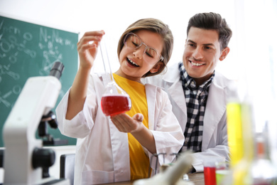 Photo of Teacher with pupil making experiment in chemistry class