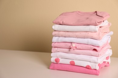 Photo of Stack of baby girl's clothes on white table. Space for text