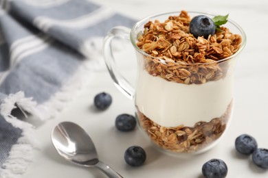 Tasty yogurt with muesli and blueberries served on white table