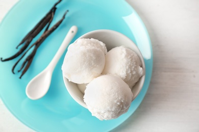 Bowl with tasty vanilla ice cream on light background, top view