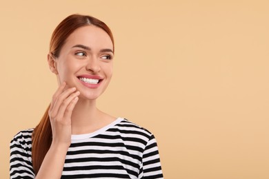 Beautiful woman with clean teeth smiling on beige background, space for text