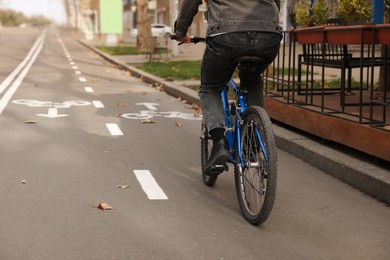 Photo of Man riding bicycle on lane in city, closeup