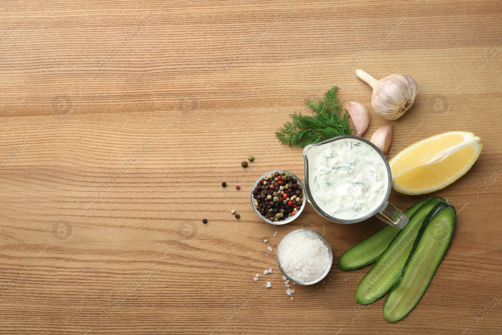 Photo of Cucumber sauce, ingredients and space for text on wooden background, flat lay. Traditional Tzatziki