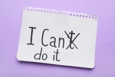 Photo of Motivation concept. Changing phrase from I Can't Do It into I Can Do It by crossing out letter T on violet background, top view