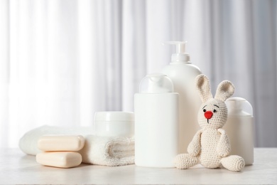 Photo of Baby cosmetic products, toy and towel on table indoors