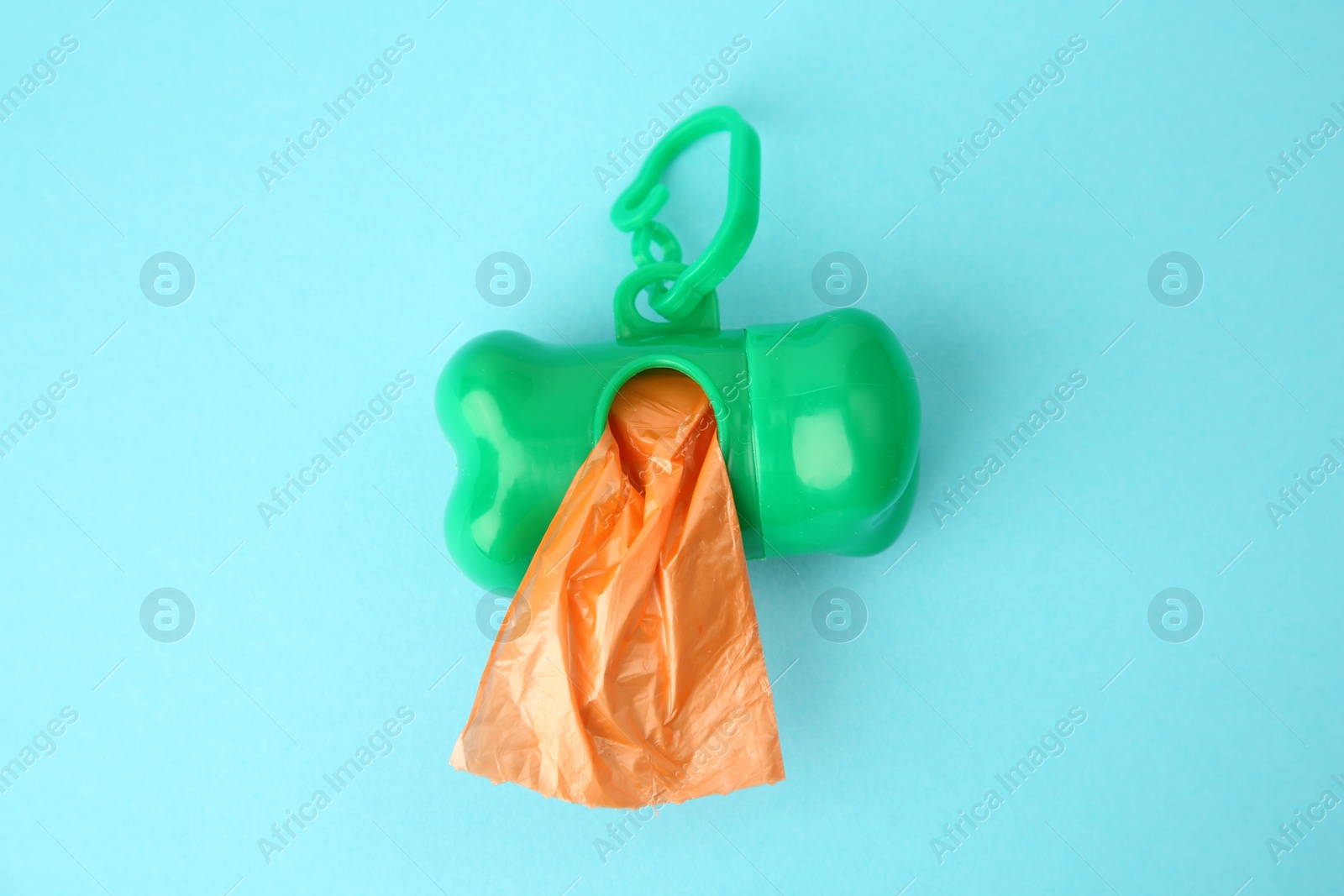 Photo of Dispenser with dog waste bags on light blue background, top view