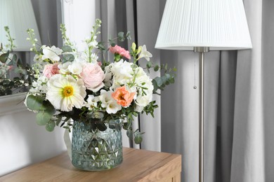 Photo of Bouquet with beautiful flowers on wooden chest of drawers indoors. Space for text