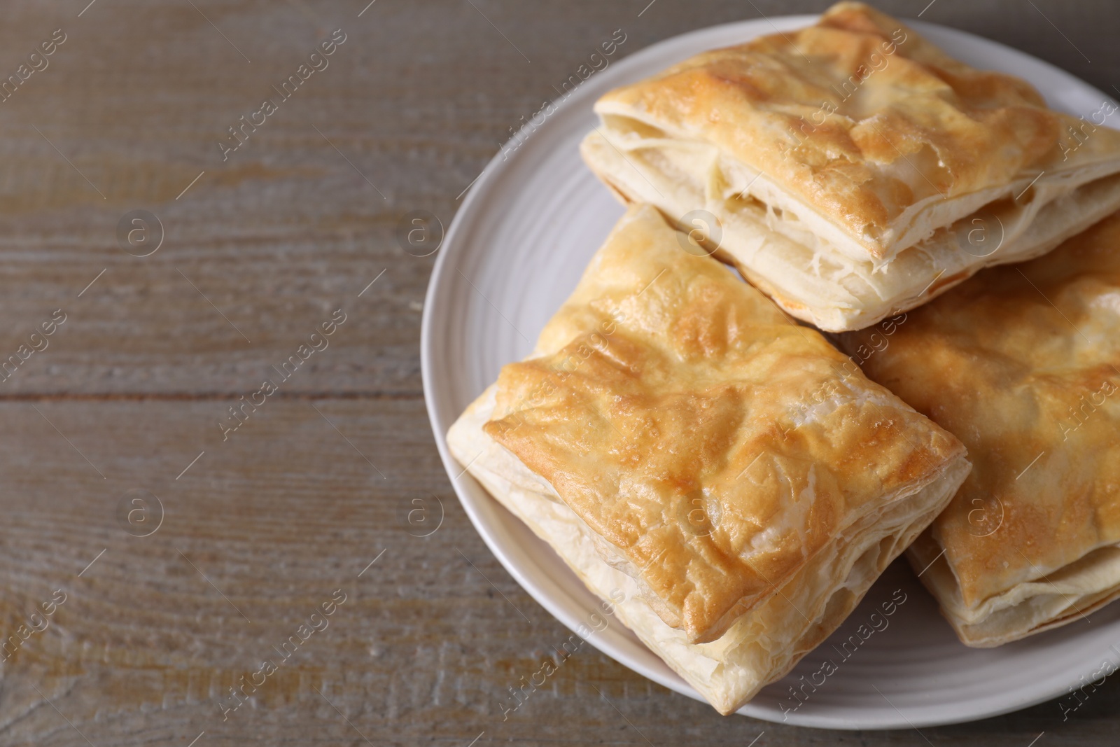 Photo of Delicious fresh puff pastries on wooden table, closeup. Space for text