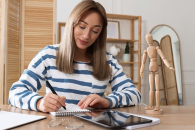 Photo of Woman drawing in sketchbook with pen at wooden table indoors