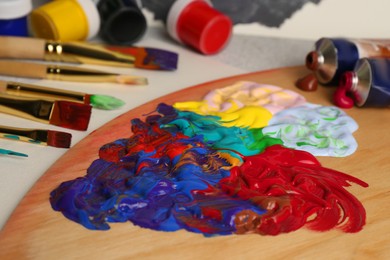 Photo of Artist's palette with mixed paints and brushes on table, closeup