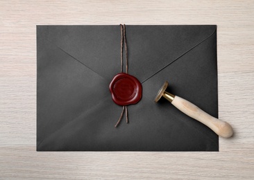 Photo of Envelope with wax seal and stamp on white wooden table, top view