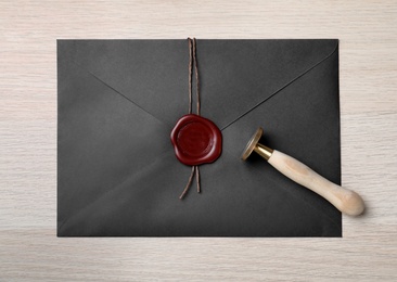 Envelope with wax seal and stamp on white wooden table, top view