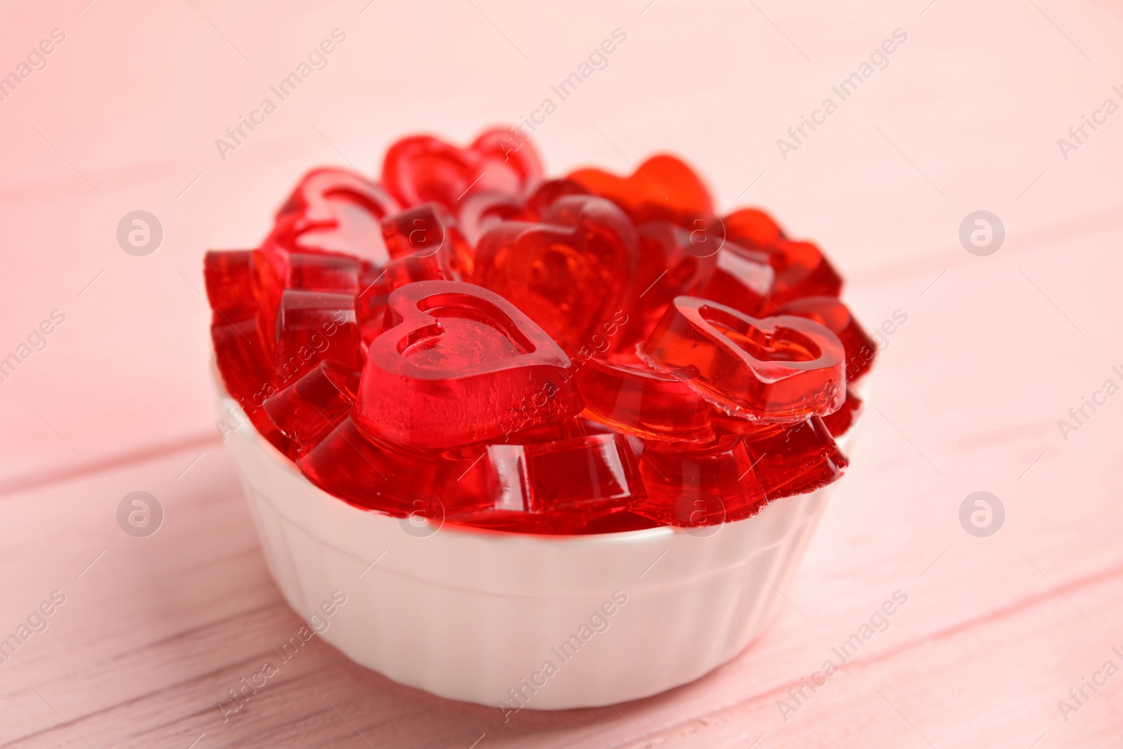 Photo of Tasty heart shaped jelly candies on pink table