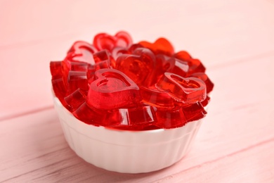 Photo of Tasty heart shaped jelly candies on pink table