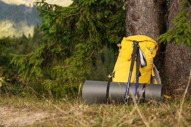 Photo of Backpack, trekking poles and sleeping mat outdoors, space for text. Tourism equipment