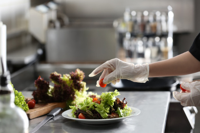 Photo of Female chef cooking tasty food in restaurant kitchen, closeup