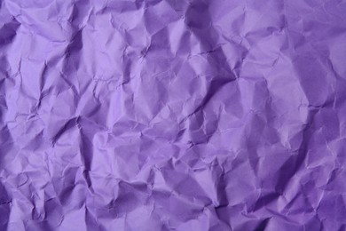 Sheet of crumpled violet paper as background, top view