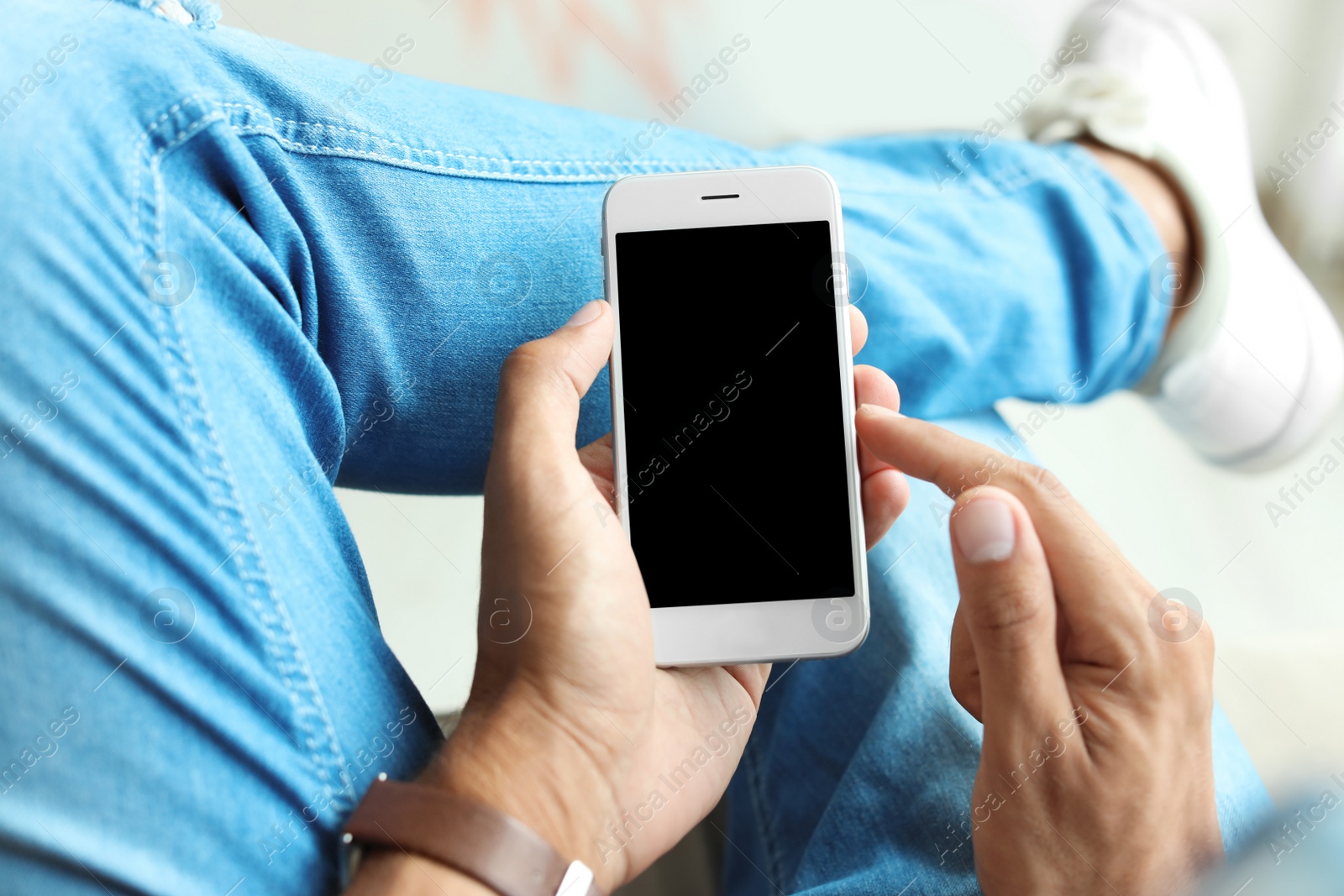 Photo of Young man holding mobile phone with blank screen, closeup