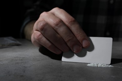 Addicted man preparing drugs for consumption at grey table, closeup