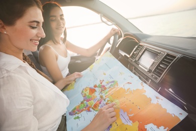 Photo of Happy friends with map in car on road trip, closeup