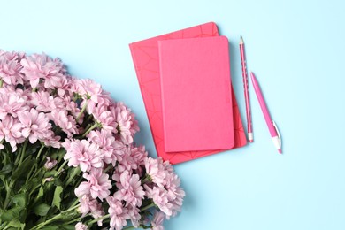 Photo of Different school stationery and beautiful pink flowers on light blue background, flat lay. Happy Teacher's Day