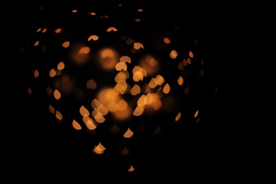 Photo of Blurred view of gold lights on dark background. Bokeh effect