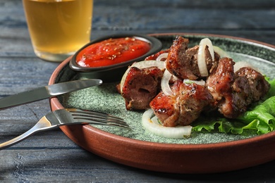 Plate with shish kebab and sauce on table, closeup