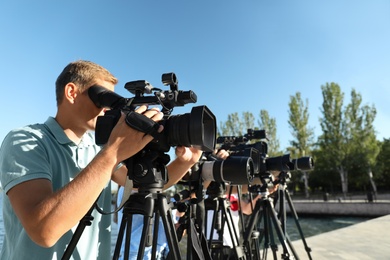 Photo of Operators with professional video cameras working outdoors on sunny day