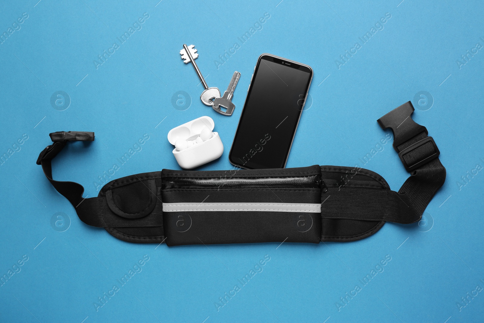 Photo of Flat lay composition with stylish black waist bag on light blue background