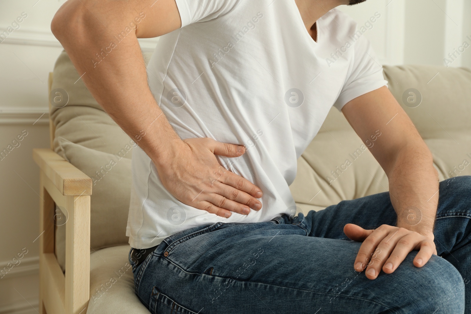 Photo of Man suffering from pain in lower right abdomen on sofa at home, closeup. Acute appendicitis