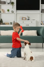 Photo of Little boy playing with his cute dog at home. Adorable pet