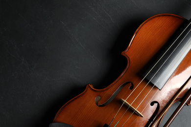 Classic violin and bow on black stone background, top view. Space for text