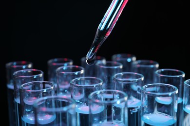 Photo of Dripping reagent into test tube on black background, closeup. Laboratory analysis