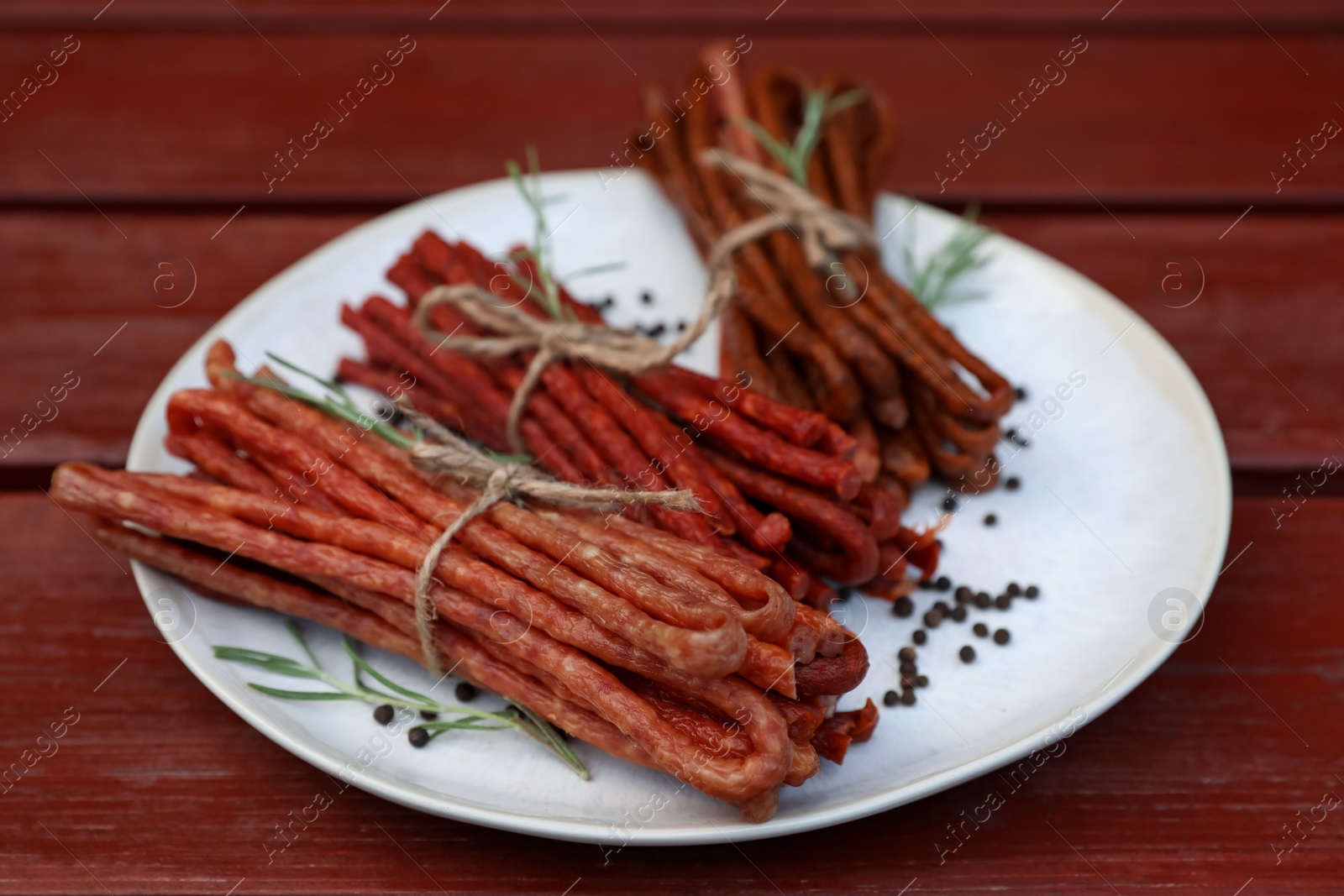 Photo of Tasty dry cured sausages (kabanosy) and spices on wooden table