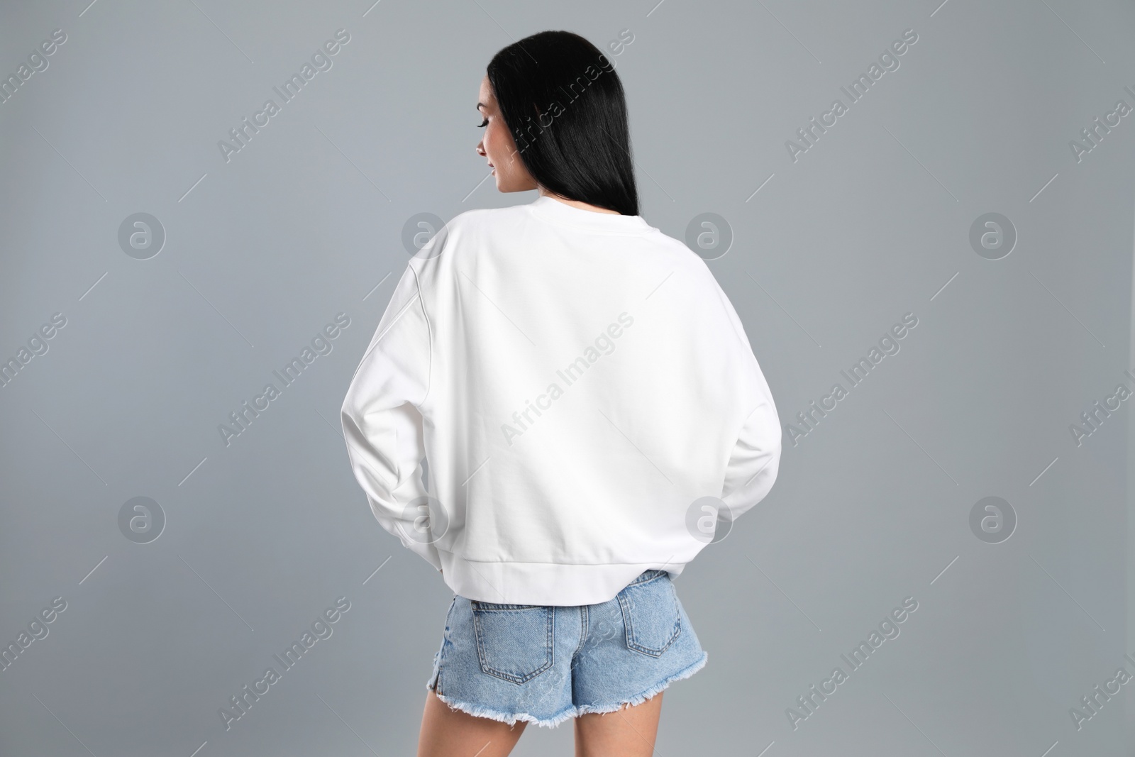 Photo of Young woman in sweater on grey background. Mock up for design