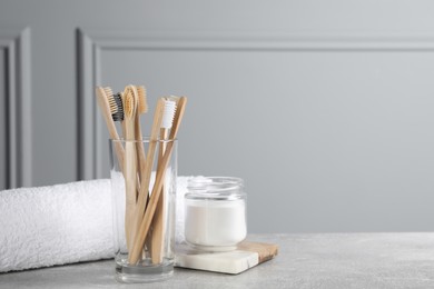 Photo of Bamboo toothbrushes, towel and jar of baking soda on light grey table, space for text