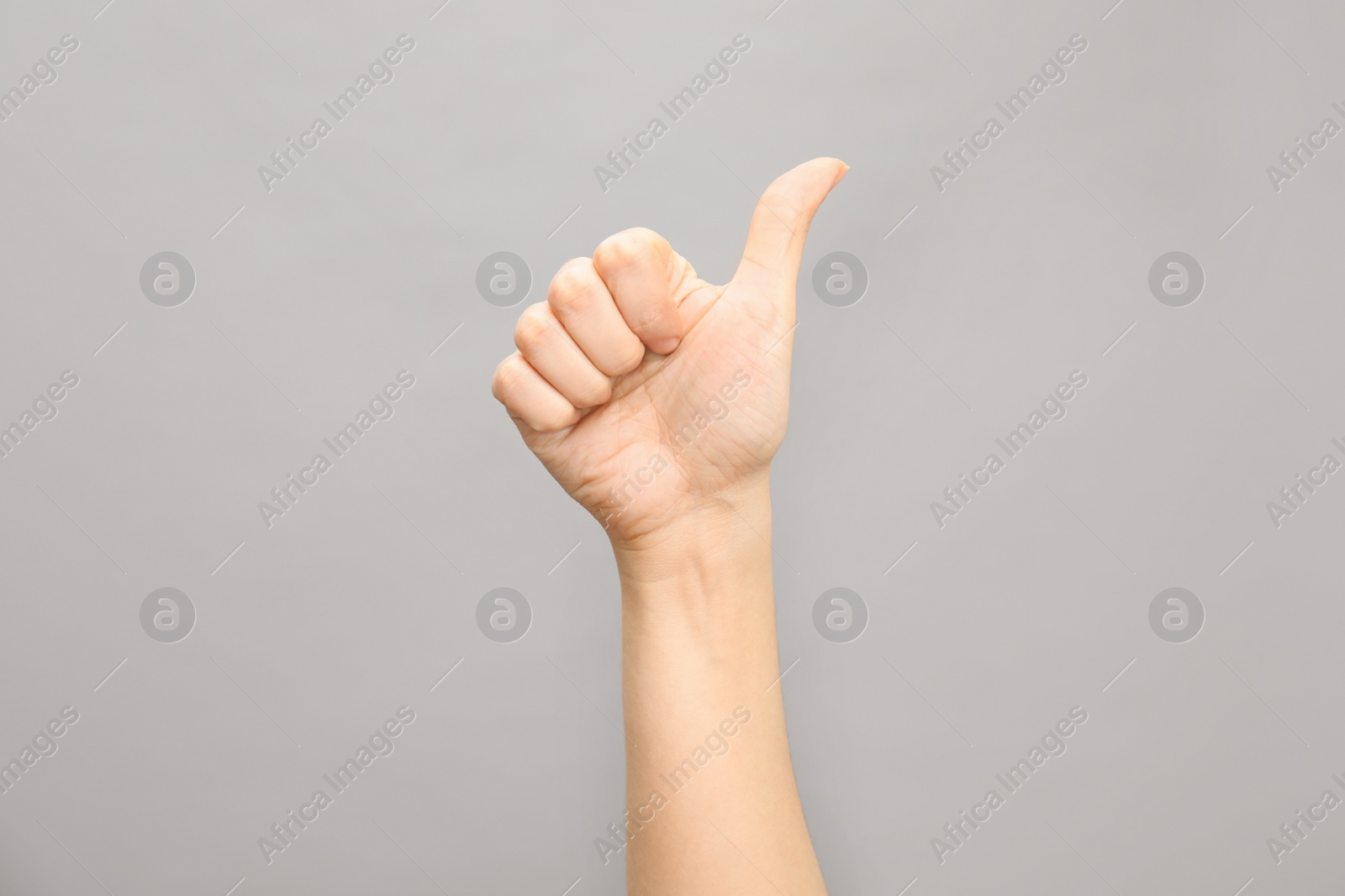 Photo of Woman showing number ten on grey background, closeup. Sign language