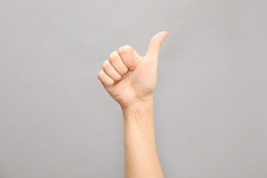 Photo of Woman showing number ten on grey background, closeup. Sign language