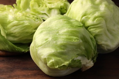 Photo of Fresh green whole and cut iceberg lettuce heads on wooden table, closeup