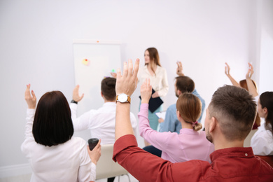 Photo of People raising hands to ask questions at business training indoors