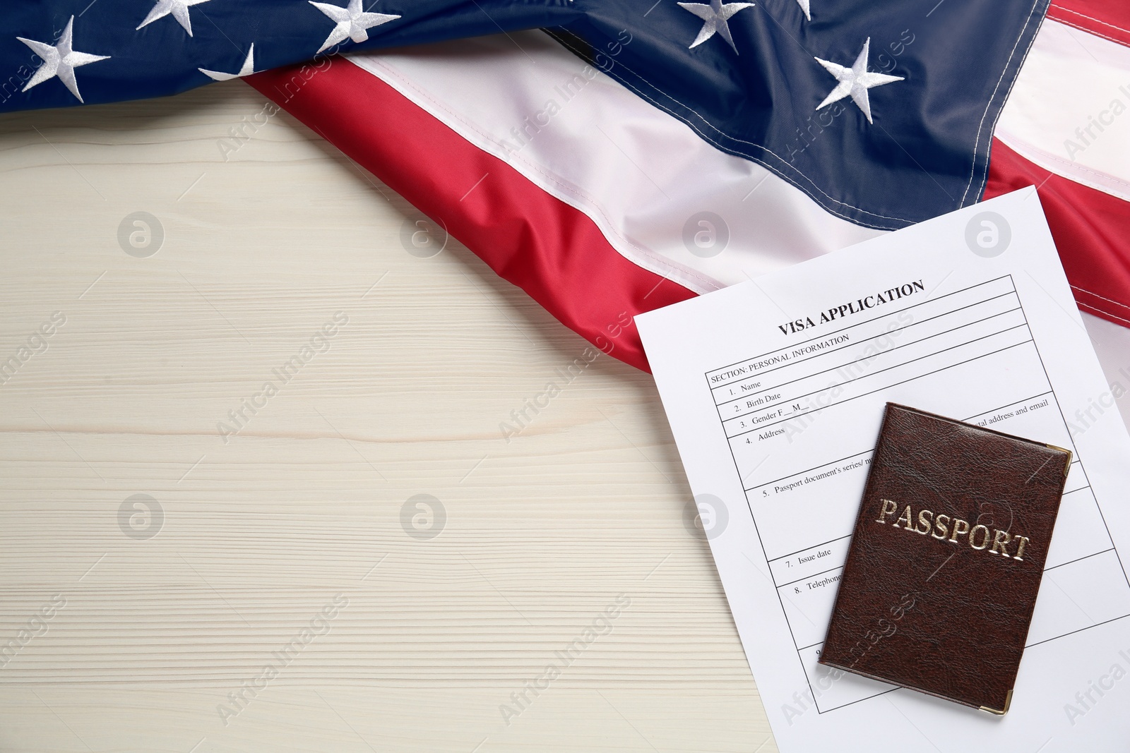 Photo of American flag, visa application form and passport on white wooden table, flat lay. Space for text