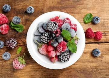 Mix of different frozen berries on wooden table, flat lay