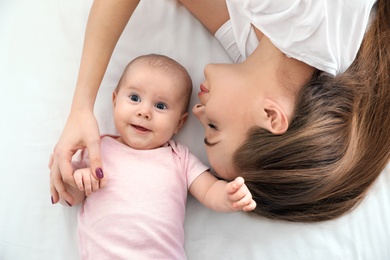 Photo of Portrait of mother with her cute baby lying on bed, top view